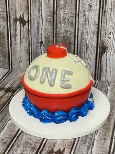 a cake that is shaped like a boat with the word one on it and blue streamers