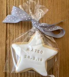 a star shaped cookie wrapped in plastic on top of a wooden table next to a ribbon