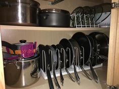 pots and pans are sitting on the shelves in this kitchen cabinet with utensils