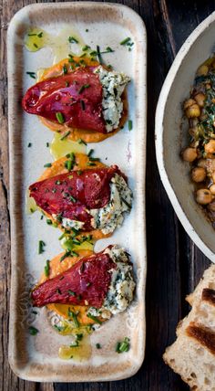 two plates with food on them next to some bread and other items that are sitting on the table