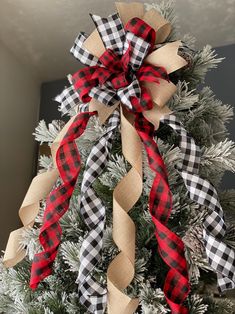 a christmas tree decorated with burlucks and plaid ribbon for the holiday season