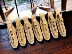 six leather bottle openers sitting on top of a wooden table next to a window