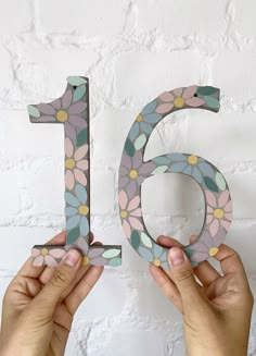 two hands holding up the number six with flowers on it