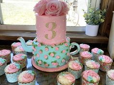 a table topped with lots of cupcakes covered in frosting and pink flowers