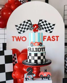 there is a birthday cake with two cars on it and balloons in the shape of hearts