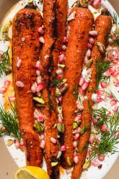 some carrots are on a white plate with garnishes and lemon wedges