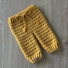 a crocheted yellow pants laying on top of a wooden floor