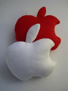 an apple pillow sitting on top of a white table next to a red and white stuffed animal