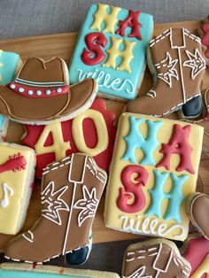 decorated cookies with cowboy hats and numbers on wooden board next to gray tablecloths