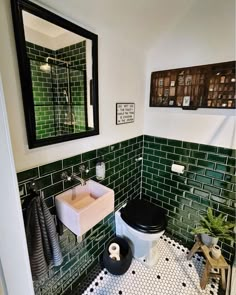 a black and white tiled bathroom with green tiles on the walls, toilet and sink