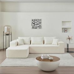 a modern living room with white furniture and art on the wall behind the sectional couch