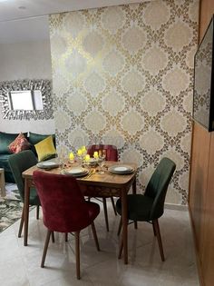 a dining room table and chairs in front of a wallpapered living room area