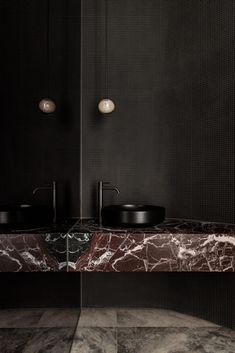 a bathroom with black walls and marble counter tops, along with two sinks in the middle