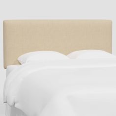 an upholstered headboard with white sheets and pillows