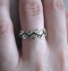 a close up of a person's hand wearing a ring with leaves on it