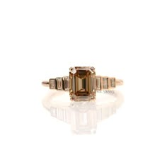 an emerald and diamond ring with three baguets on the side, set in yellow gold