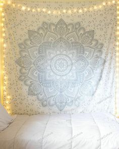 a bed with a white comforter and lights on the headboard, in front of a wall