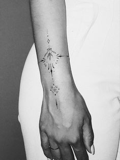 a black and white photo of a woman's arm with a tattoo on it