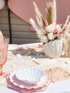 the table is set with pink and white plates, vases, and other decorative items