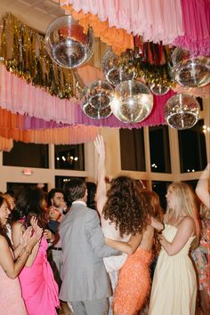 a group of people that are standing in the middle of a room with disco balls hanging from the ceiling