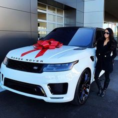 a woman standing next to a white car with a red bow on it