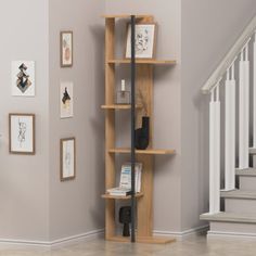 a wooden book shelf sitting in the corner of a room next to a stair case