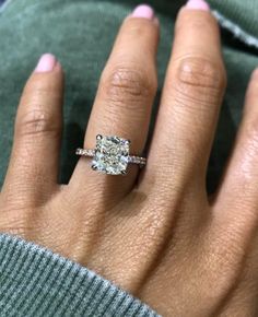 a woman's hand with a diamond ring on her left hand and the other hand holding an engagement ring