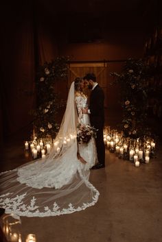 a bride and groom kissing in front of candles