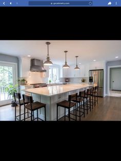 a large kitchen with an island and lots of stools in the middle of it