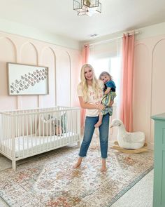 a woman standing next to a baby in a room