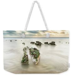 some rocks on the beach with water and clouds in the background weekend tote bag by panoramic images