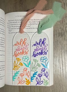 two bookmarks with the words and flowers on them are next to an open book