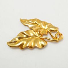 100% authentic gorgeous vintage Kenzo brooch with double-leaf motif in goldtone metal, signed Kenzo at the backBrand: KenzoColor: Gold-toneMaterial: Gold-tone metalCondition: Excellent condition Measurements: Width 6 cm x Height 8.5 cmAccessories: NoneCondition Rankings:Mint - Perfect condition and presents as brand new. No indication of handling or marks.Excellent - Nearly mint condition with only very minor evidence of handling.Very Good - Evidence of handling with no major flaws or wear.Good Gold Leaf Brooch For Gift, Vintage Gold Leaf Jewelry, Vintage Gold Leaf-shaped Jewelry, Designer Costume Jewelry, Best Purses, Leaf Motif, Leather Clutch Bags, Vintage Bags, Gold Tone Metal