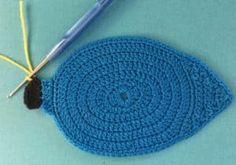 a crocheted blue piece of cloth next to a knitting needle