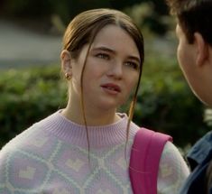 a woman in a pink sweater talking to a man