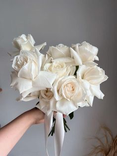 a bouquet of white roses being held by someone's hand