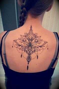 the back of a woman's shoulder with an intricate tattoo design on her upper