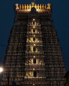 the top of an ornate building lit up at night