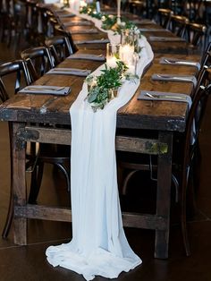 a long table with candles and greenery is set up for an elegant wedding reception