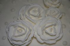 four white roses are sitting on top of a cake