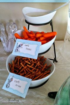 carrots and other food items are displayed in bowls on a table with place cards