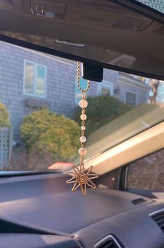 a car dashboard with a sun charm hanging from the dash board, in front of a house