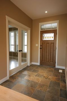 an empty room with two doors and a window in the center is seen from across the room