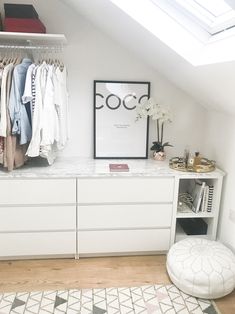 a white closet with clothes hanging on the wall and a rug in front of it