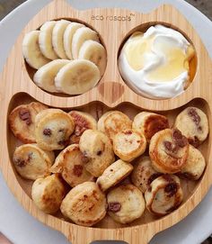 a wooden plate topped with banana slices and other foods on top of a white plate