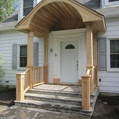 a white house with a wooden porch and steps leading up to the front door area