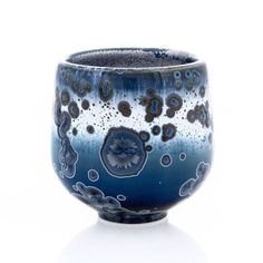 a blue and white cup with bubbles on it's rim, against a white background