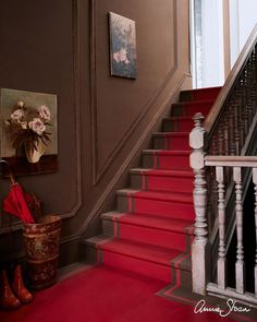 a red carpeted staircase leading up to a painting on the wall