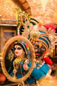 a woman in blue and gold costume holding a mirror with her face painted on it