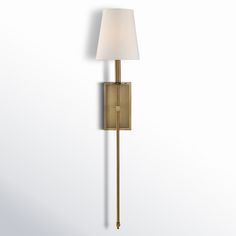 a wall light with a white shade on the side and a gold metal pole attached to it